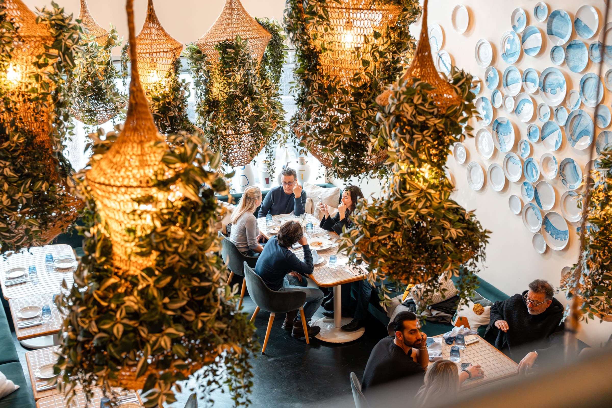 Diners beneath the hanging greenery and lantern canopy