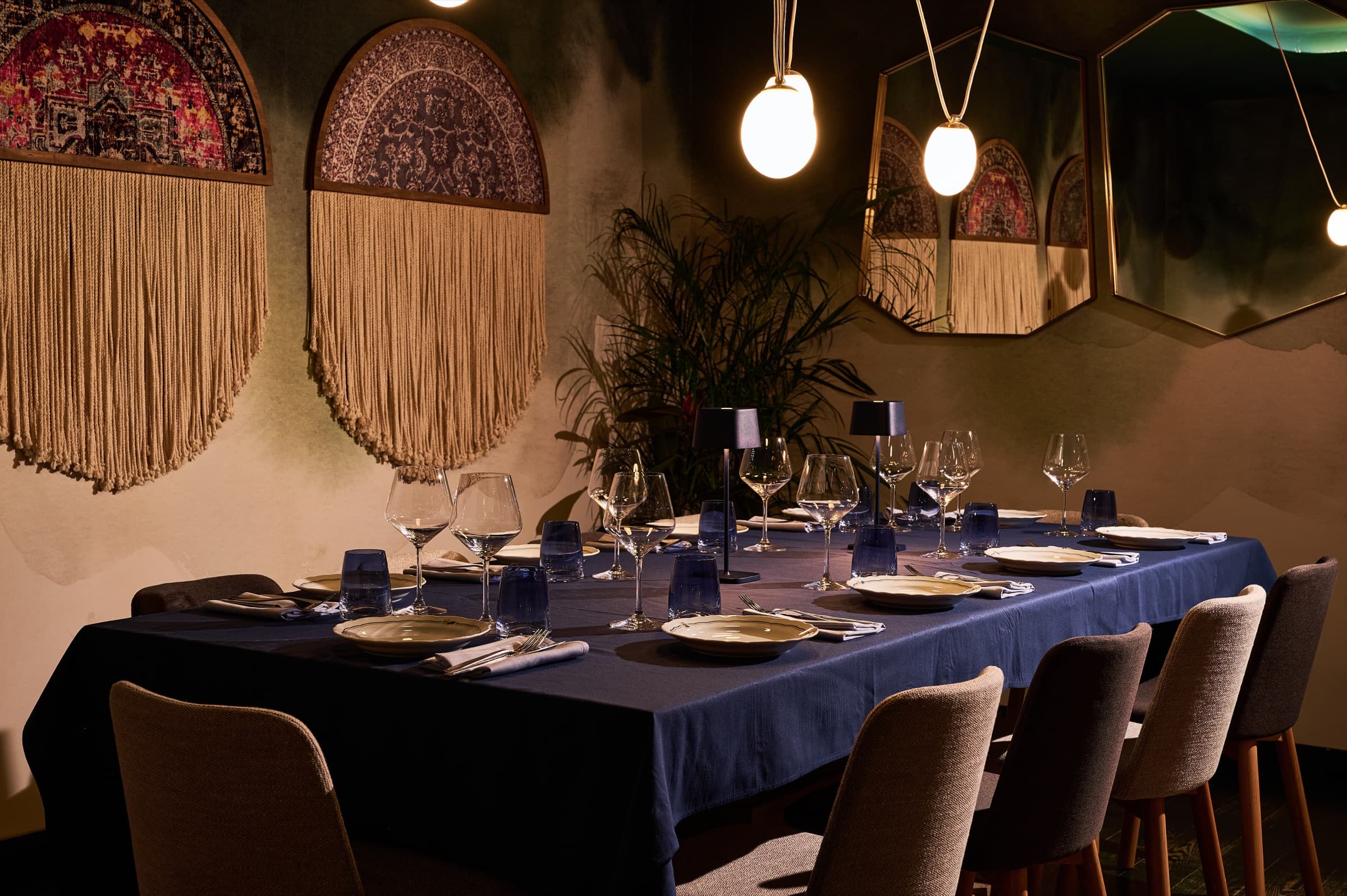 Private dining room at Meláni set for a long table dinner beneath macramé wall hangings